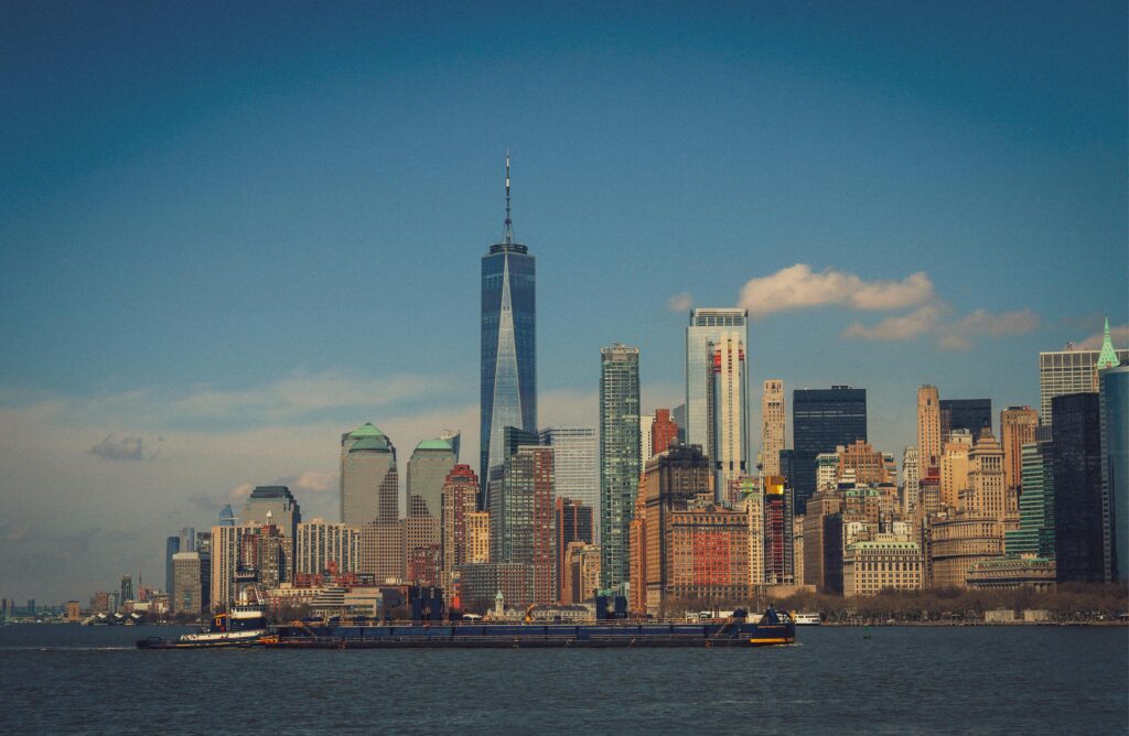 Majestic view of New York City's skyline with One World Trade Center and surrounding skyscrapers under a blue sky.